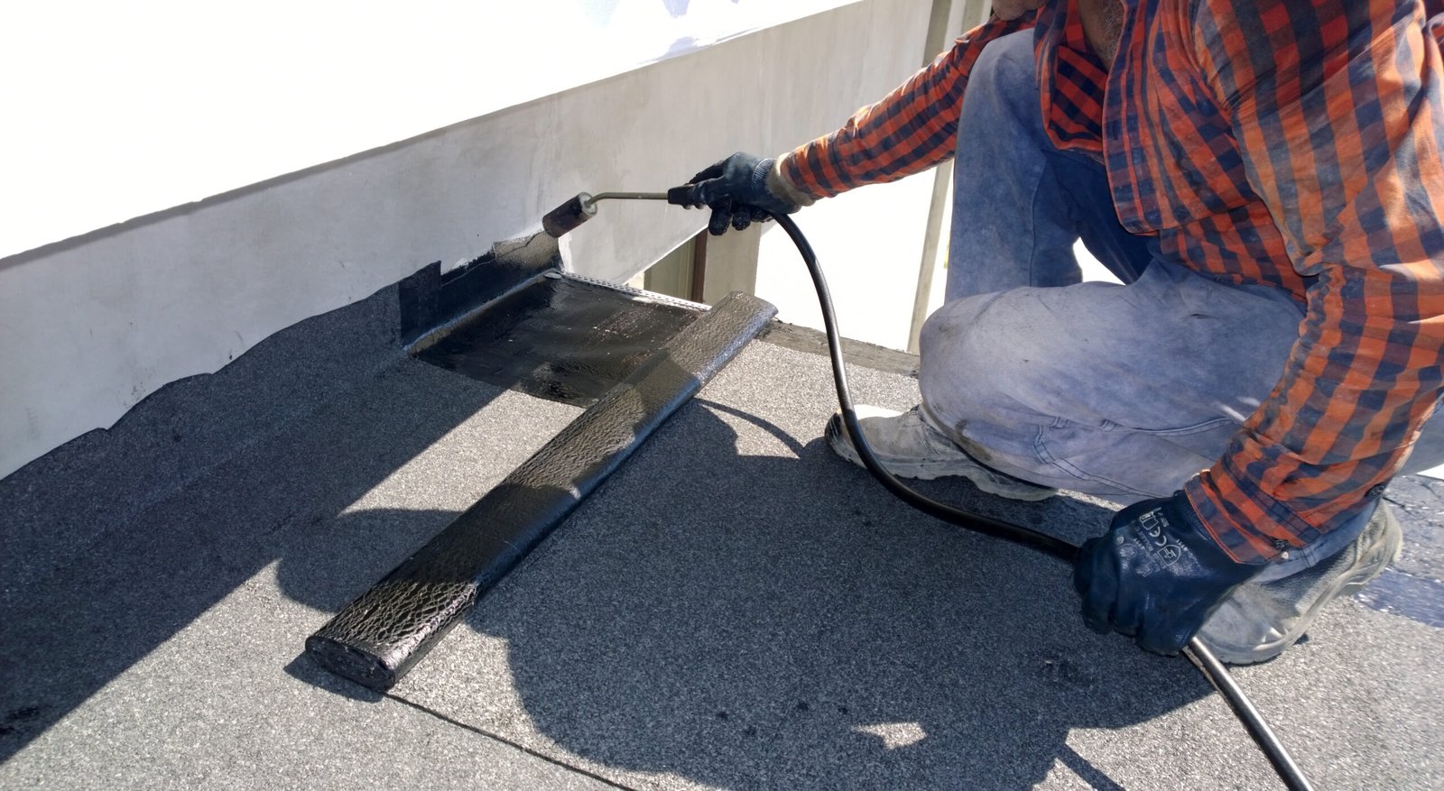 ajax-roof-repair1 Roofer repairing part of bitumen roofing felt roll on a commercial building roof top in Ajax, On