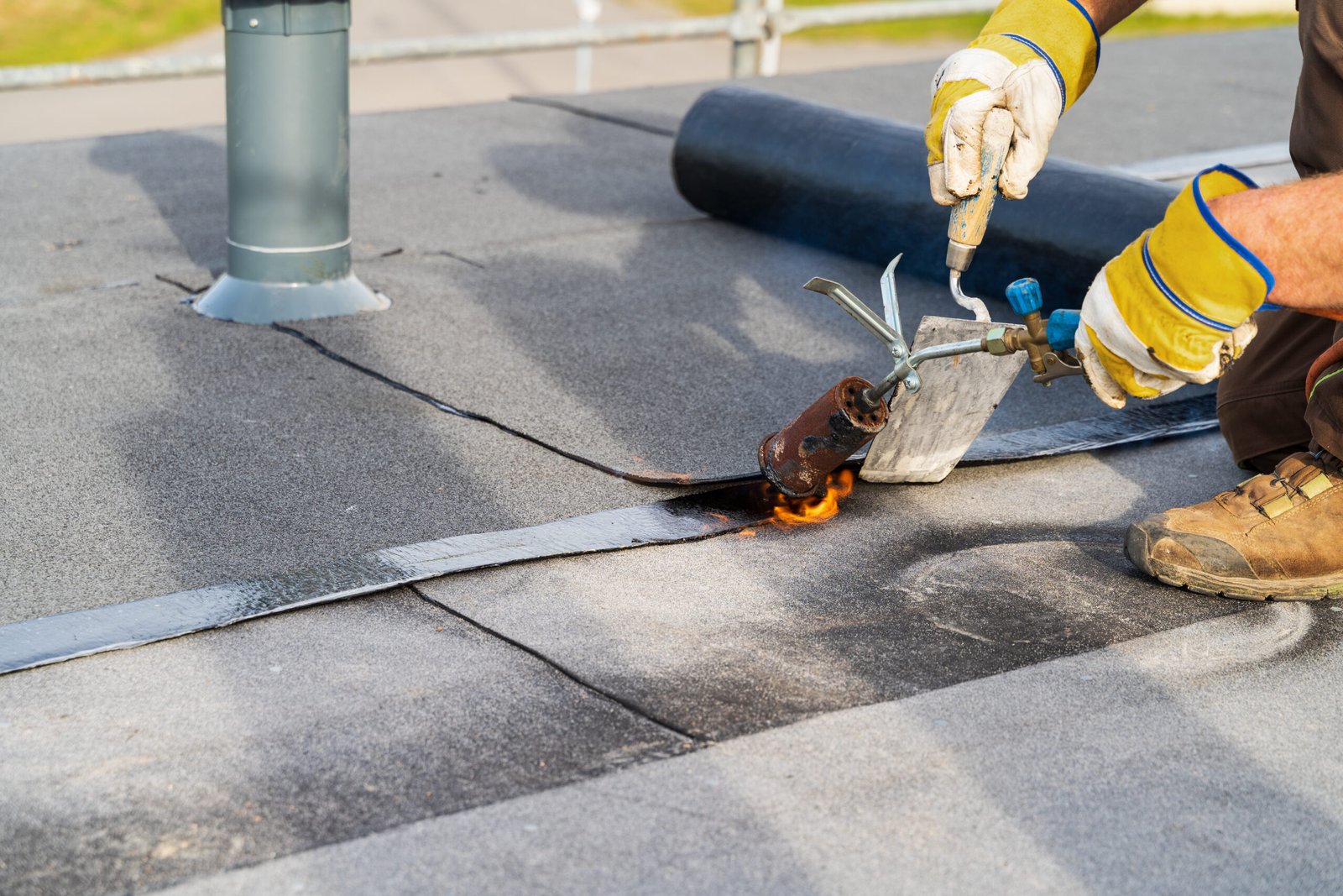 Roofer Heating and melting bitumen roofing commercial flat roof installation.