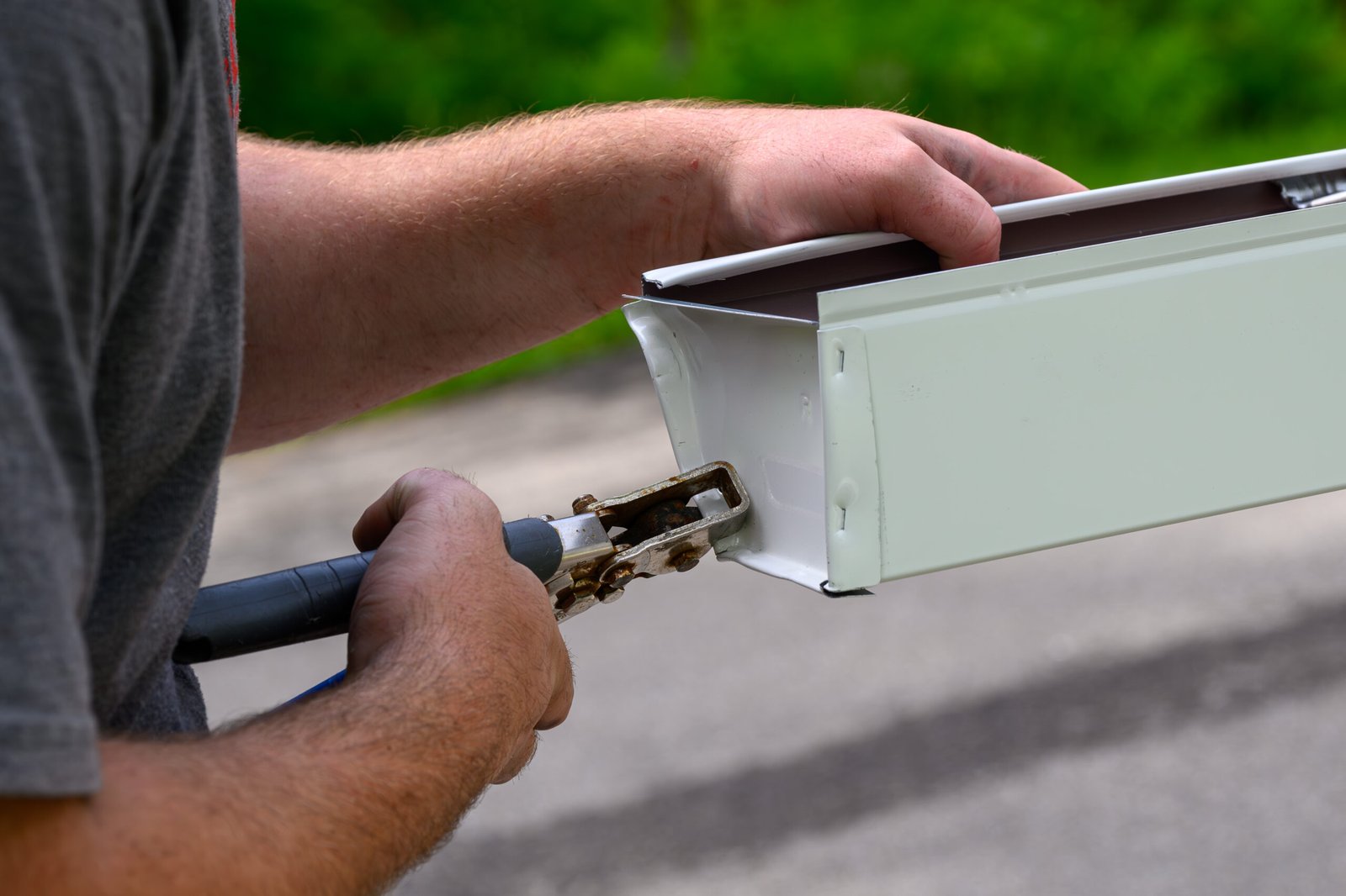 Hands of a roofing technician in the process of installing custom made gutters on a home in Ajax, preparing gutters for installation.