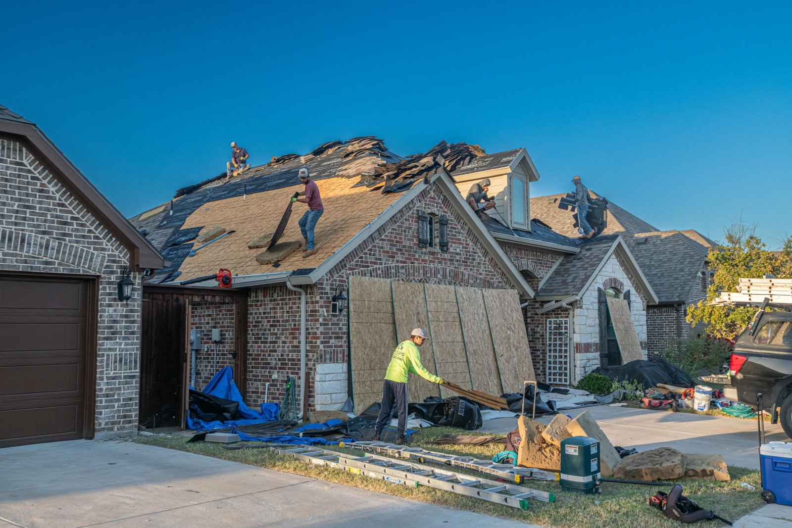 Roofing crew in Ajax removing old asphalt shingles off a house